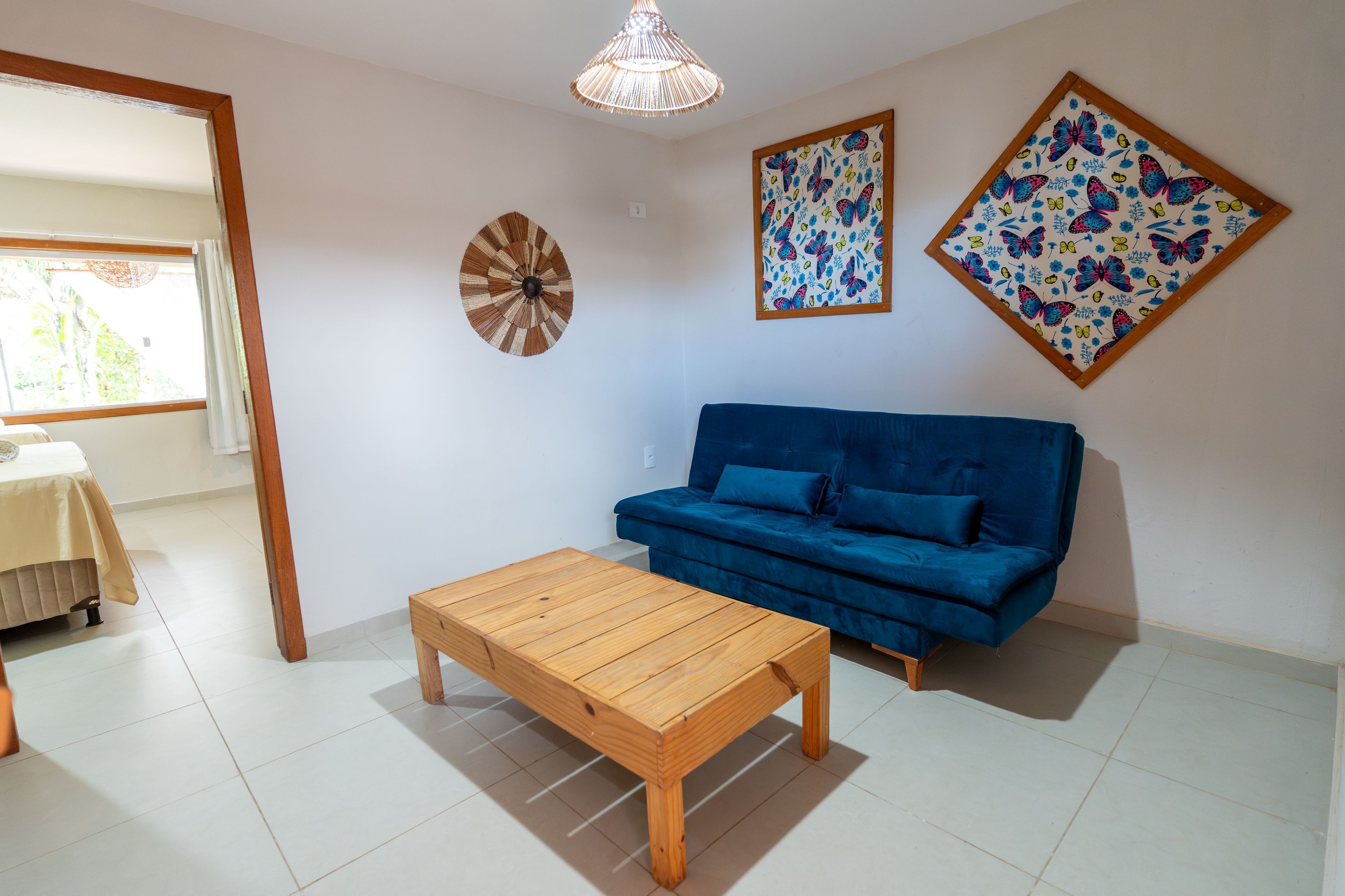 Ein Wohnzimmer mit einem Holztisch, einem blauen Sofa und zwei Wandbehängen mit Schmetterlingsmuster.