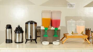 A coffee station with a coffee maker, thermos, and two juice dispensers.