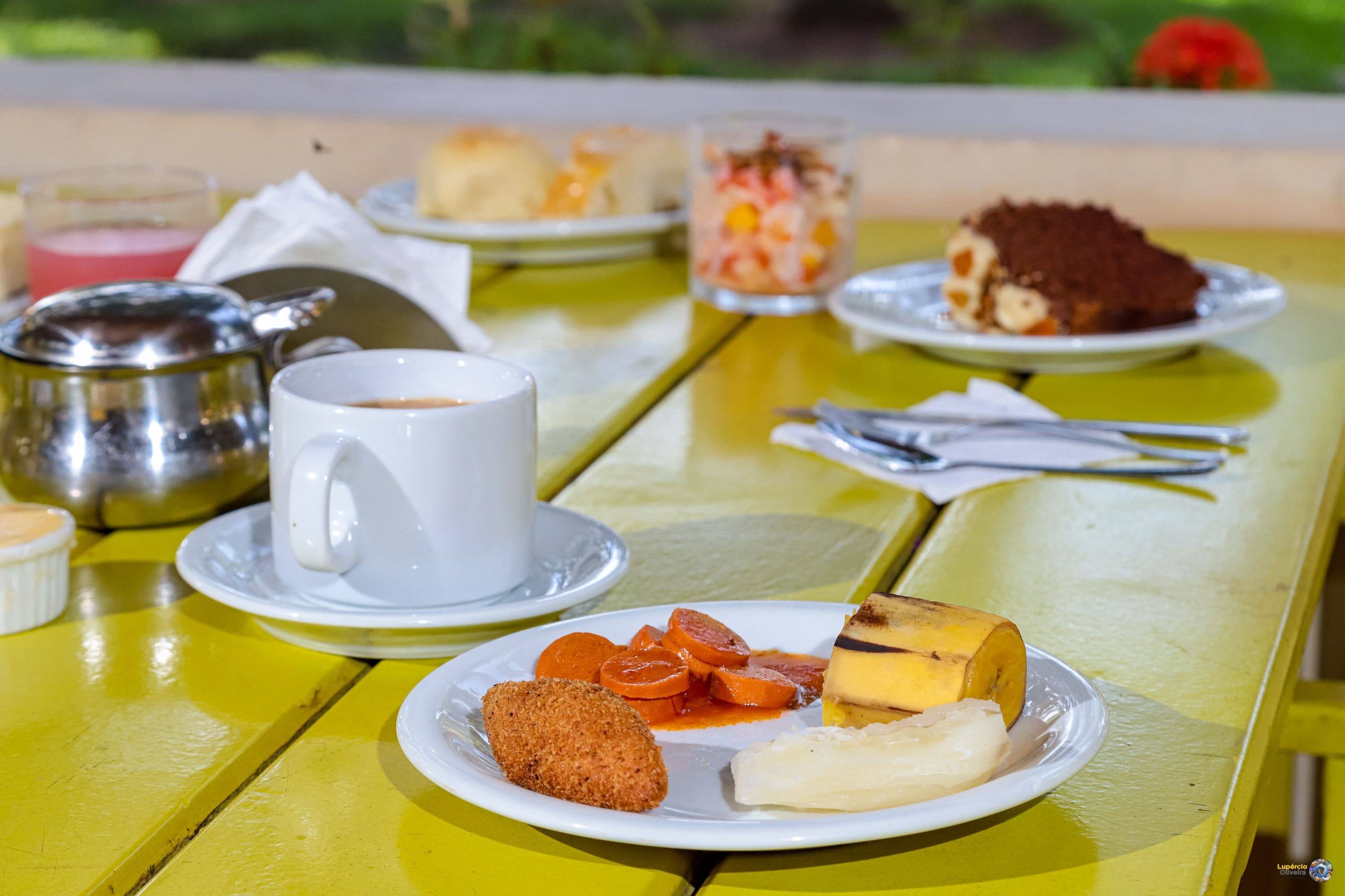 A table with a variety of food items including a croissant, a banana, and a dessert on a yellow table.