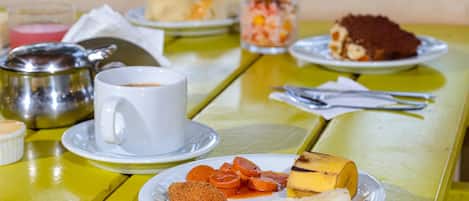 A table with a variety of food items including a croissant, a banana, and a dessert on a yellow table.
