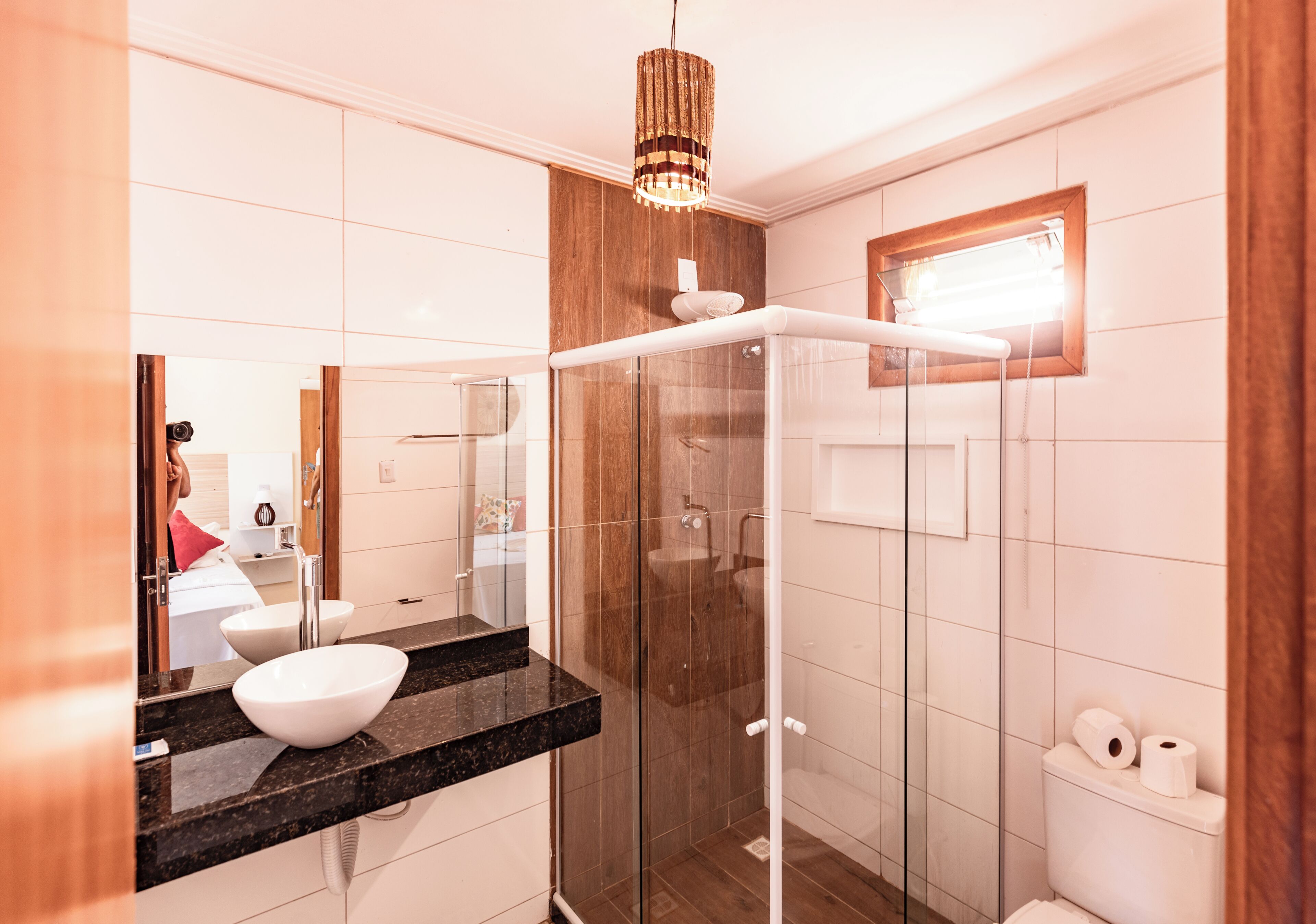 A modern bathroom with a glass shower enclosure, a white sink with a marble countertop, and a wooden vanity.