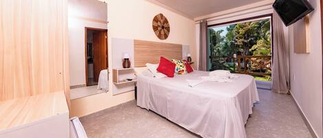 Ein Hotelzimmer mit Bett, Fernseher, Nachttisch, Spiegel und Blick ins Freie.