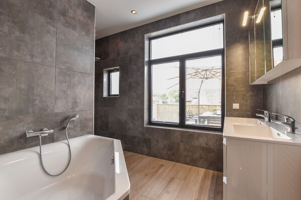 A modern bathroom with a bathtub, a window, and a sink. - Spacious Apartment in the Center of Yerseke (Yerseke)