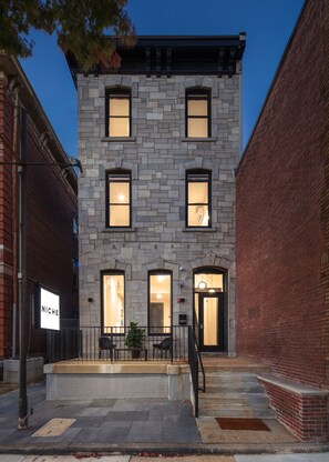 A two-story building with a stone facade, multiple windows, and a black door. - Kasa The Niche University City Philadelphia (Philadelphia)