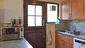 Cocina compacta equipada con microondas, tostadora, lavabo y lavadora.