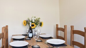 Una mesa de comedor dispuesta con platos blancos, copas de vino y una botella de vino.