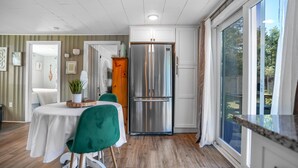 A modern kitchen with a stainless steel refrigerator, wooden cabinets, and a dining area with a table and chairs. - New England Lake House (Lakeville)