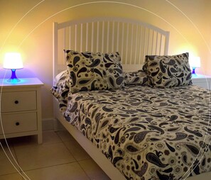 A bedroom with a bed, two bedside tables, and a nightstand.