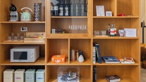 A wooden shelving unit with various items including wine bottles, glasses, a bicycle, a kettle, and storage containers. - Napoli Visit Home (Naples)