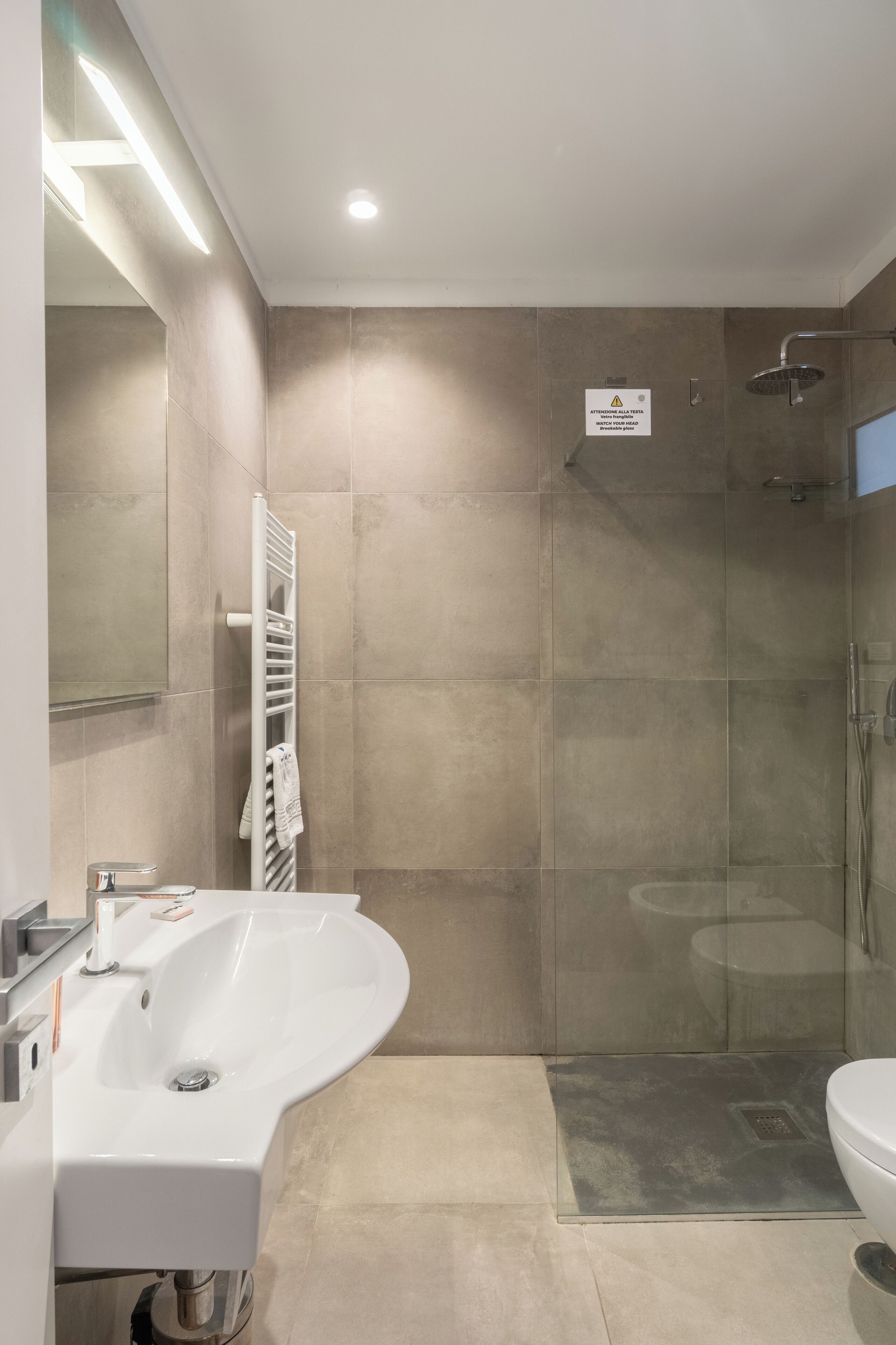 Une salle de bain moderne avec un grand lavabo, une douche à parois de verre et un porte-serviettes.