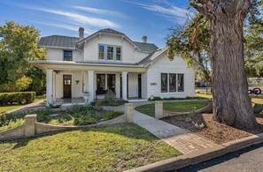 Stunning two-story house with a central entrance, covered porch, and beautifully landscaped grounds.