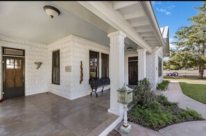 Welcome to a charming entrance with a covered porch, lantern-style lighting, and a beautifully maintained lawn.
