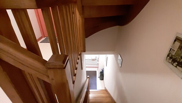 A wooden staircase with a curved ceiling, leading to a room with a red door and a framed picture on the wall. - F2 apartment near the spa. (La Bourboule)