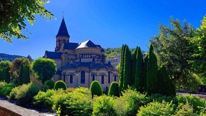 A historic building with a prominent tower, surrounded by well-maintained gardens and trees. - F2 apartment near the spa. (La Bourboule)