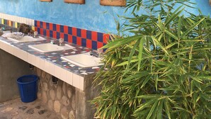 A bathroom with a blue wall, a tiled sink area, and a bamboo plant. - Iguana Azul - Hostel (Copan Ruinas)