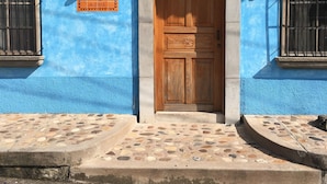A building with a blue facade, a wooden door, and a tiled entrance. - Iguana Azul - Hostel (Copan Ruinas)