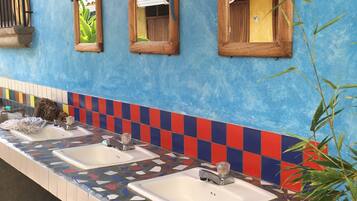 Un baño público con tres lavamanos, una pared de azulejos azules y un letrero de madera que dice "AZUL".