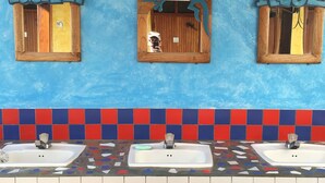 A bathroom with three sinks, a mirror, and two wall-mounted signs reading "IGUANA" and "AZUL". - Iguana Azul - Hostel (Copan Ruinas)