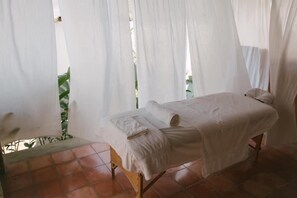 Une pièce avec un lit, une petite table et un rideau.