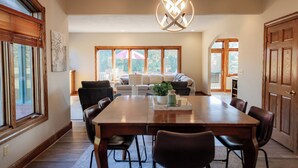 A dining area with a wooden table and chairs, a chandelier, and large windows with blinds. - Indoor Gymnasium, Seasonal Pool, 7 Bedroom, Sleeps 28 (Fort recovery)