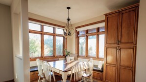 A dining area with a wooden table and chairs, large windows, and wooden cabinetry. - Indoor Gymnasium, Seasonal Pool, 7 Bedroom, Sleeps 28 (Fort recovery)