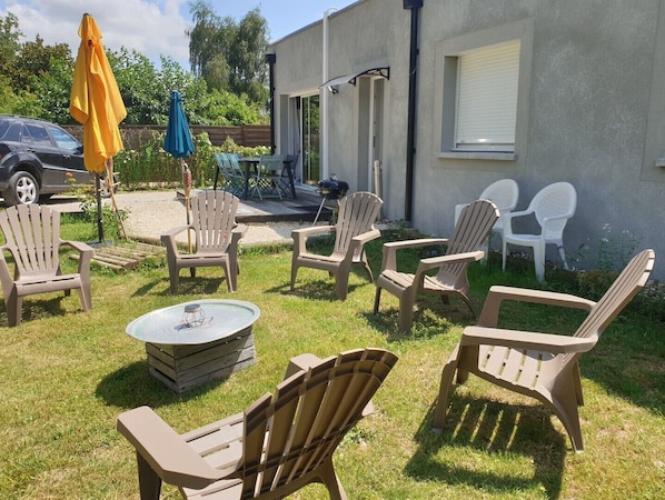 An outdoor patio area with Adirondack chairs, a round table, and a yellow umbrella.