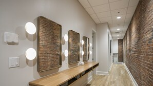 A hallway with a wooden bench, mirrors, and a brick wall. - The Record Room -steps to Broadway & Printer’s Alley (Nashville)