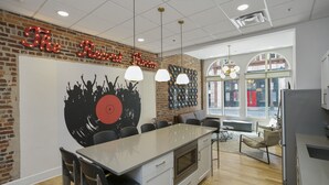 A modern kitchen with a central island, pendant lighting, and a brick accent wall with a vinyl record mural. - The Record Room -steps to Broadway & Printer’s Alley (Nashville)