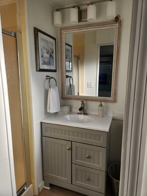 Une salle de bain avec un meuble-lavabo, un grand miroir et une serviette accrochée au mur.