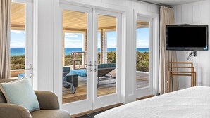 Ett hotellrum med en stor säng, en tv som är monterad på väggen och en balkong med utsikt över havet.