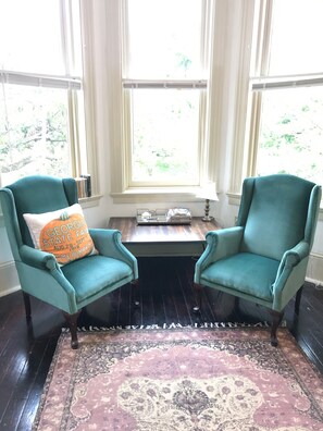 Relax in this traditional room with two armchairs, a small table, and a lamp, offering a view of lush greenery.