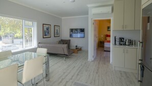 Una sala de estar moderna con una mesa de vidrio, un sofá y un televisor montado en la pared.