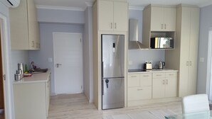 Una cocina moderna con un refrigerador de acero inoxidable, armarios blancos y un microondas en la encimera.