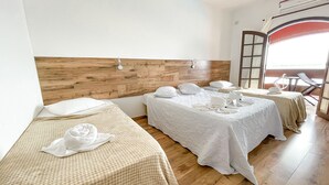 A hotel room with two beds, wooden headboards, white linens, and a view of the outdoors through a large window. - Hotel Marazul (Cananeia)
