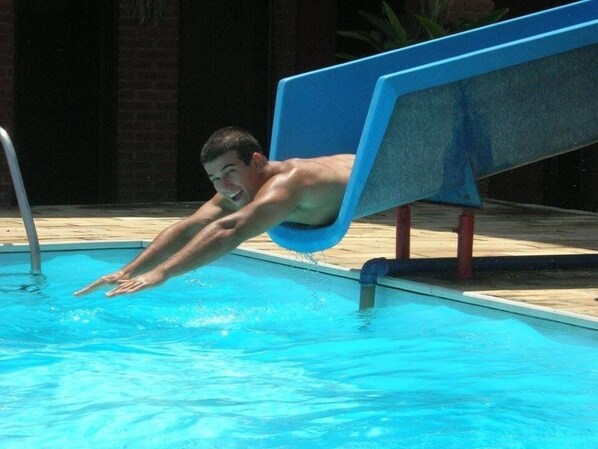 Una persona se desliza en una piscina desde un tobogán azul.