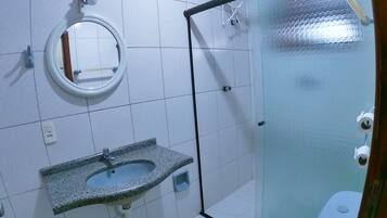A bathroom with a granite sink, a mirror, a toilet, and a shower area.