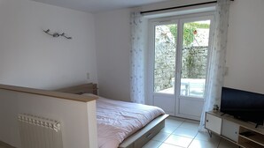 Un dormitorio con cama, televisor, radiador y puerta corrediza de vidrio a un balcón.