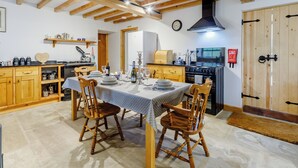 A dining area with wooden chairs and a table set for four, a kitchen with a stove and oven, and a fire exit sign.