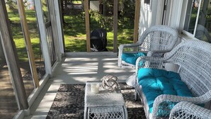 A covered porch with wicker furniture, including a sofa and chairs, and a patterned rug. - Lakefront Paradise - Sleeps 6 - Only $400/Night (Pulaski)