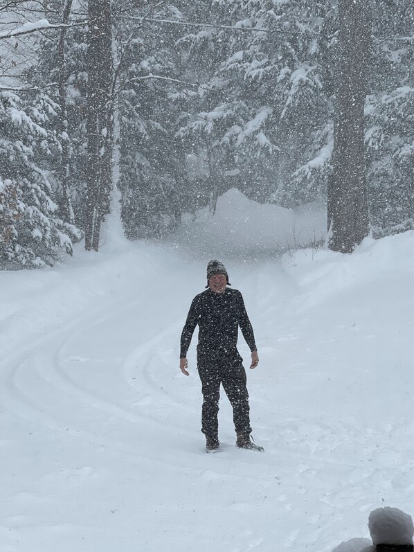 A person snowboarding down a snowy path surrounded by trees.