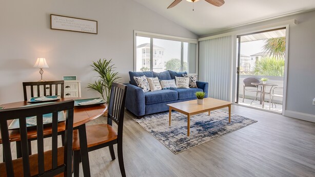 A modern living room with a blue sofa, wooden coffee table, and a ceiling fan. - Cozy Condo, 3 Minute Walking Distance to the Beach (Destin)
