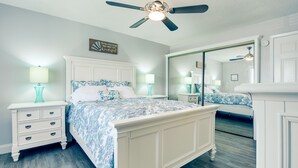 A bedroom with a bed, nightstands, a ceiling fan, and a large mirror. - Cozy Condo, 3 Minute Walking Distance to the Beach (Destin)
