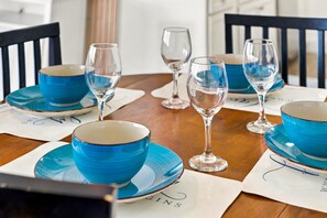 Une table à manger avec des bols bleus et des verres à vin, le tout disposé pour quatre personnes.