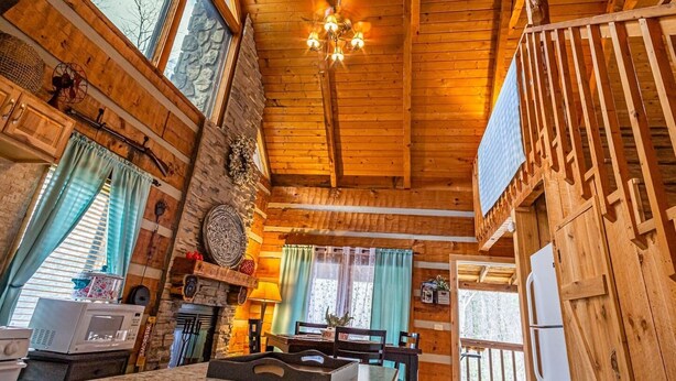Ein rustikales Holzinterieur mit Essbereich, Küche und großen Fenstern.