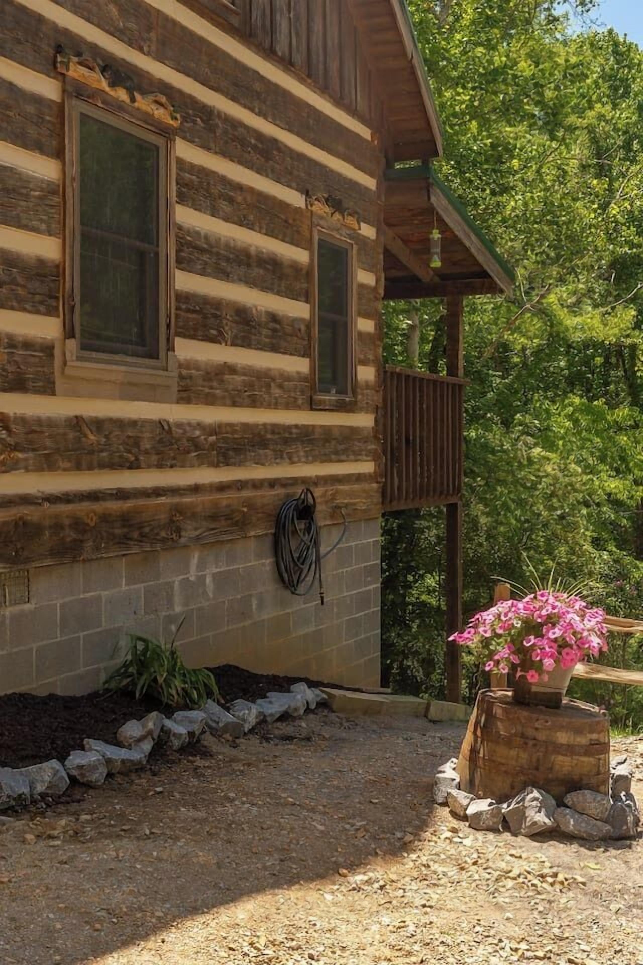 A log cabin with a wooden porch and a flower pot.