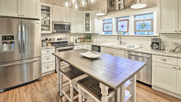 A modern kitchen with white cabinetry, stainless steel appliances, and a wooden island. - Country-Chic Cotter Home w/ Outdoor Living Space! (Cotter)