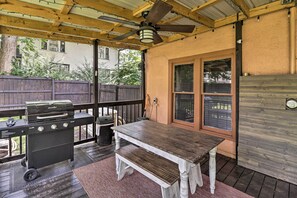 An outdoor patio with a wooden table and grill, a ceiling fan, and a view of a neighboring house. - Country-Chic Cotter Home w/ Outdoor Living Space! (Cotter)