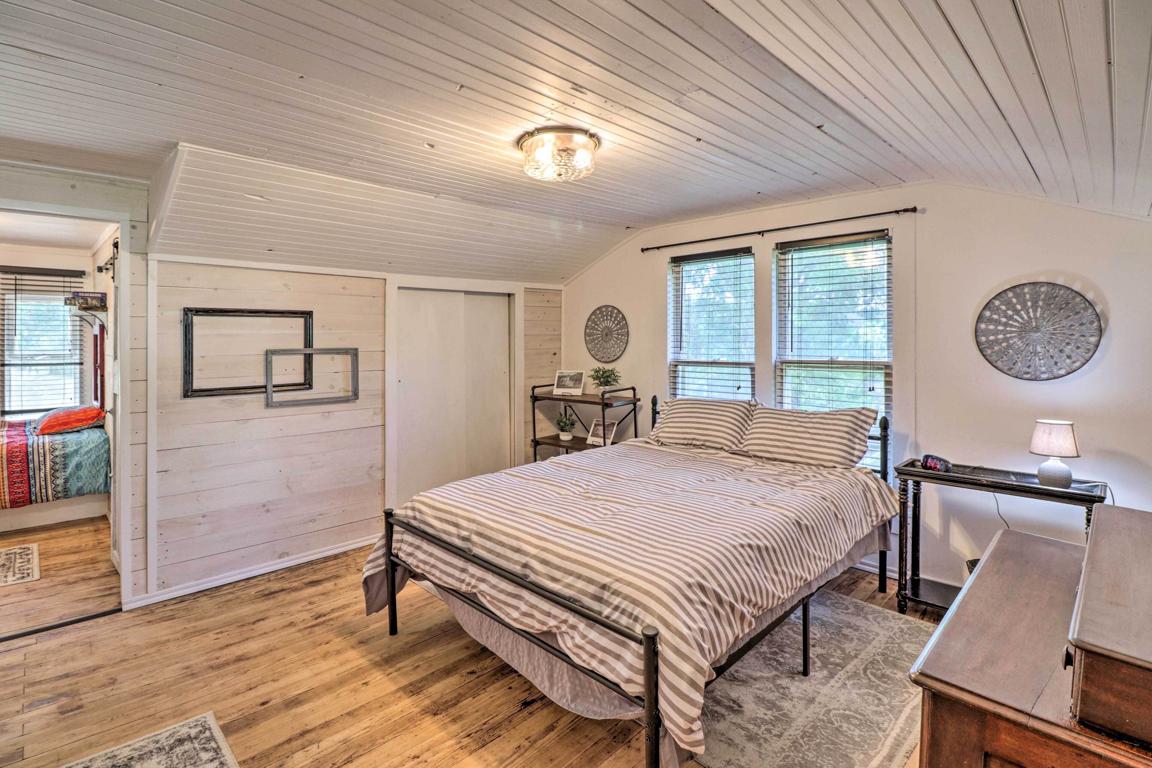 A bedroom with a bed, a desk, a chair, a lamp, and a window with blinds.