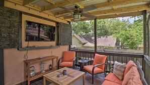 A covered outdoor patio with wooden furniture, a ceiling fan, and a view of a residential area. - Country-Chic Cotter Home w/ Outdoor Living Space! (Cotter)