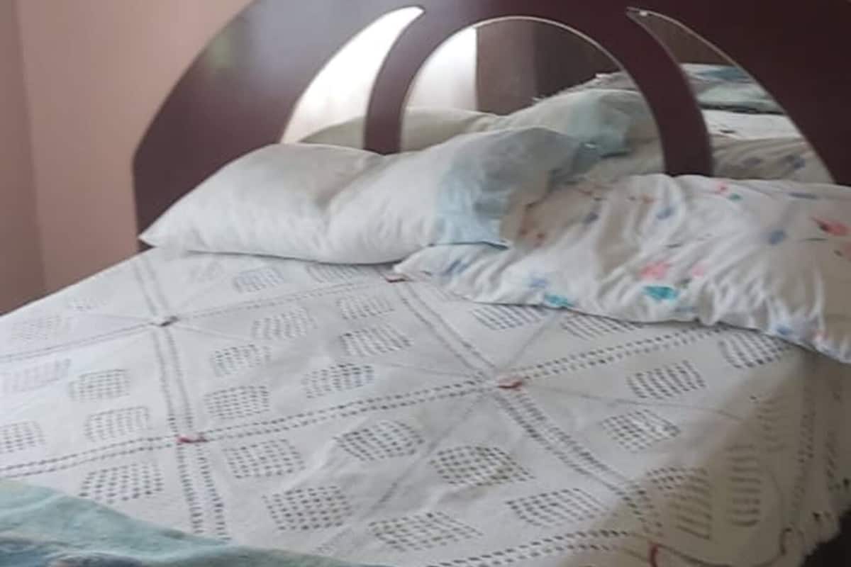 A bed with a wooden headboard, a patterned bedspread, and pillows.